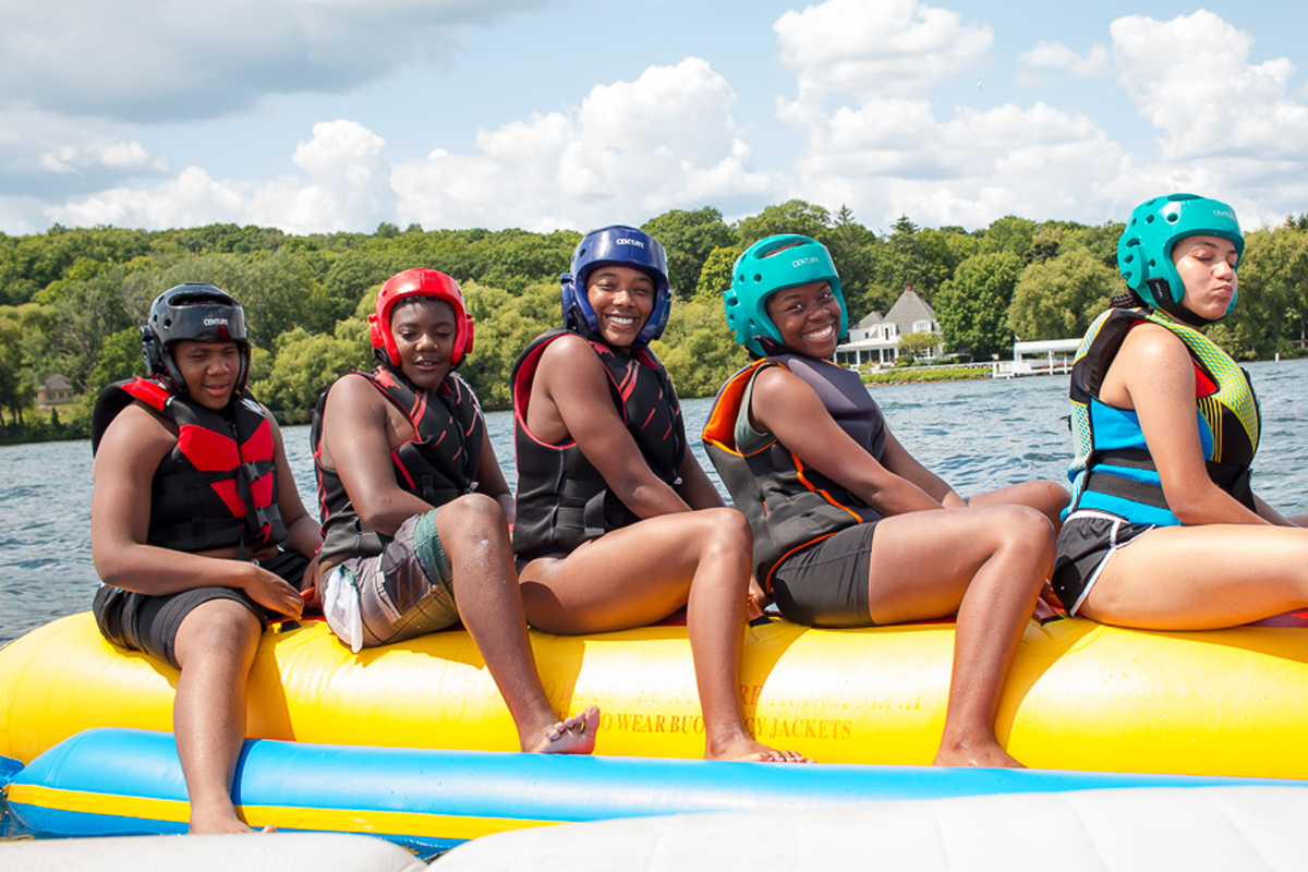 Five students on a banana boat smiling at the camera